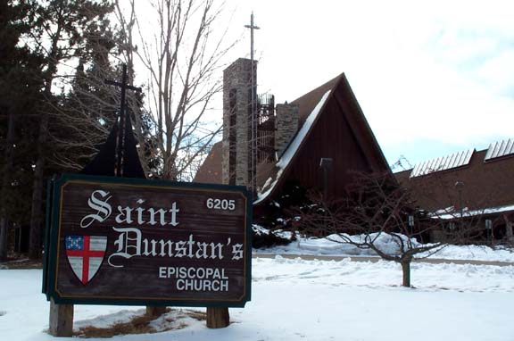St. Dunstan's Episcopal Church, 6205 University Ave., Madison, Wis., with snowcovered ground and wooden sign in foreground.