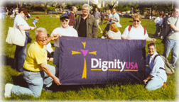 picture of Dignity members in grassy field holding banner with DignityUSA logo